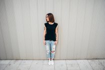 Frontansicht einer jungen Frau, die an einer Metallwand steht — Stockfoto