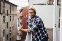 Hombre sonriente posando con café en el balcón - foto de stock