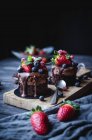 Вкусные сладкие шоколадные торты, украшенные различными ягодами на деревянном столе . — стоковое фото