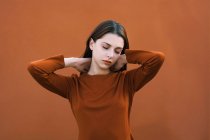 Beautiful brunette in brown posing with closed eyes against brown background — Stock Photo
