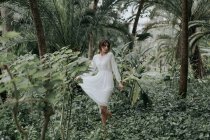 Romantic girl in white dress walking in green garden — Stock Photo
