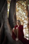 Tender woman in dress sitting on huge tree — Stock Photo