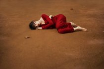 Morena menina deitada descalça no chão marrom agachado . — Fotografia de Stock