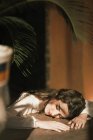 Woman in white dress lying and sleeping on wooden table. — Stock Photo