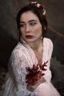 Brunette femme en blanc posant avec branche rouge — Photo de stock