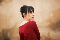 Alluring girl in red dress looking over shoulder away — Stock Photo