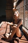 Блондинка сидить на балконі на сонячному світлі з закритими очима — стокове фото