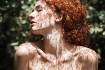 Redhead woman standing sensually in shadows of lace with eyes closed — Stock Photo