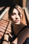 Young blond girl looking unemotionally at camera in sunrays. — Stock Photo