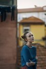 Mulher loira posando contra casas da cidade com braços cruzados — Fotografia de Stock
