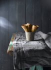 Composición de conos de gofre en taza sobre mesa rústica - foto de stock