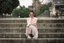 Stylish woman in skirt sitting on steps abd looking at camera — Stock Photo