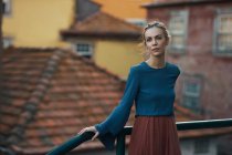 Frau steht am Geländer in der Stadt und blickt in Kamera — Stockfoto