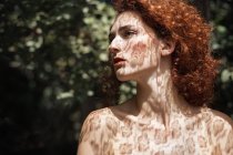 Sensual ginger girl posing in shadows of lace — Stock Photo