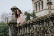 Curly woman in glasses leaning on handrail of terrace — Stock Photo