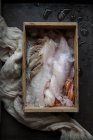 Trop vue du poisson cru et des différents fruits de mer dans la glace dans une boîte en bois. — Photo de stock