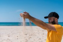 Mann schüttet Sand auf Strand — Stockfoto
