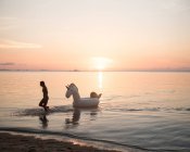 Frau mit aufblasbarem Pferdespielzeug im Meer — Stockfoto