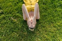 Mujer acostada en la hierba con las manos en la cara - foto de stock