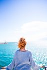 Жінка стоїть на поручнях і дивиться на океан — стокове фото