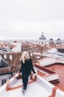 Блондинка сидить на даху — стокове фото
