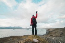 Чоловік стоїть біля озера з піднятою рукою — стокове фото