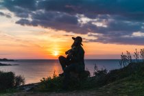 Mann sitzt mit Gitarre an Küste — Stockfoto