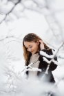 Mujer de pie entre ramas de invierno - foto de stock