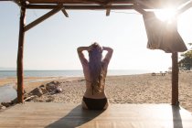 Женщина сидит на песчаном солнечном пляже — стоковое фото