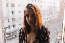 Young woman standing at window — Stock Photo
