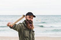 Человек с палкой и цветами в бороде — стоковое фото