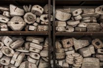 Crop view of different white forms for pouring clay and iron on shelves in foundry — Stock Photo