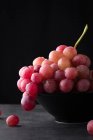 Червоний виноград у чорній мисці — стокове фото