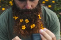 Man with yellow flowers in beard — Stock Photo