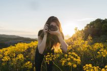 Mulher tirando foto com flores amarelas — Fotografia de Stock