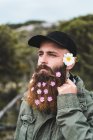 Человек с фиолетовыми цветами в бороде — стоковое фото