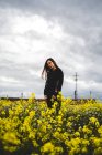Mulher de pé no gramado com flores amarelas — Fotografia de Stock