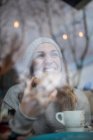 Mujer mordiendo galleta en la cafetería - foto de stock