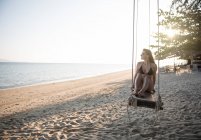 Femme relaxant sur les balançoires sur la plage — Photo de stock