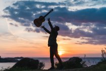 Человек веселится с гитарой на берегу — стоковое фото