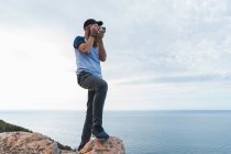 Hombre tomando foto en roca - foto de stock