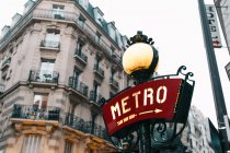 Panneau rouge du métro avec flèche et bâtiment traditionnel, Paris, France — Photo de stock