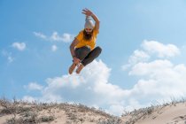 Mann springt auf sandigen Hügel — Stockfoto