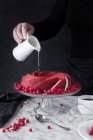 Hand gießt Sahne auf Kuchen — Stockfoto
