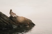 Frau steht auf Küstenfelsen — Stockfoto