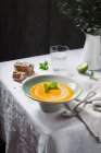 Tigela de sopa de abóbora laranja apetitosa servida na mesa rústica . — Fotografia de Stock
