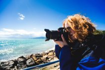 Mujer tomando fotos en la costa - foto de stock