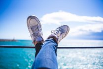 Beine am Geländer am Meer — Stockfoto