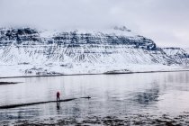 Passeggiata turistica irriconoscibile al lago freddo in montagne innevate in Islanda. — Foto stock