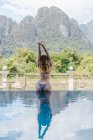 Femme en bikini debout au bord de la piscine — Photo de stock